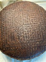 Top view of the round lid showing detailed woven dark brown pattern.