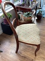 Side view of antique wooden chair showing the curved backrest and patterned upholstered seat