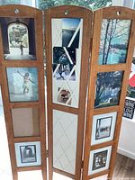 Full front view of the wooden three-panel room divider showing multiple photo frames with photos inserted.