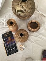 Top view of all four pottery items showing shapes and surface carvings with Sinclair Ceramics brochure and tag