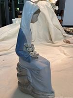 Side view showing seated woman in blue and white dress holding white flowers