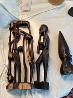 Overall view of three wooden Jamaican carved figures on a white cloth background.