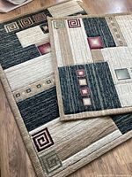 Photo showing both rugs with geometric abstract patterns laid out on wooden floor to show size and design