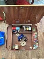 Open sewing basket interior showing various thread spools and accessories, with compartments.
