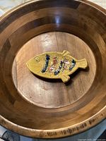 Top view showing yellow ceramic fish-shaped ashtray inside large wooden bowl.