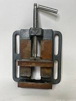 Top view of cast iron drill press vise showing the mounting slots and screw with handle.