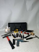 Photo showing full assortment of tools on black plastic tray, including tape measure, hammers, screwdrivers, socket set and other hand tools