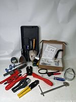 Full array of plumber's tools including Ridgid PEX crimp tool, Apollo tool, cutters, Allen keys, wrenches, tape, screwdriver, and metal tray.