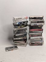 Two stacks of approximately 30 cassette tapes showing titles and artists.