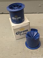 Blue plastic lime cutter standing on white Corona Extra branded box, showing front logo and cutter parts