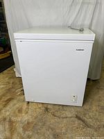 Front view of Koolatron white chest freezer with lid closed and power cord coiled on top, showing Koolatron logo on front panel.