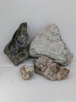Four mineral specimens displayed against a white background showing size and detail.