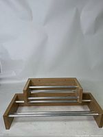 Photo of small wooden jewelry display rack showing wooden frame and 3 metal rods horizontally placed for hanging necklaces or jewelry.