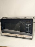 Front view of Panasonic microwave oven showing door, control panel and power cord on top.