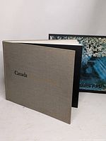 Photo book open showing beige cloth cover with gold embossed title 'Canada A Year of the Land'