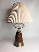 View of the vintage mid-century modern table lamp with pleated beige shade, brass accents, and ceramic brown body with starburst design.