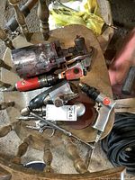 Overview of multiple air tools laid on a wooden chair showing sprayer, ratchet, drill, and other tools with clear wear and usage marks.