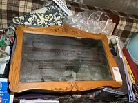 Front view of antique oak framed mirror showing carved details on the frame and tarnished mirror glass.