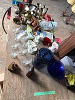 Overview of various brass, glass, ceramic, cast iron, and wooden items displayed on a wooden table.