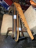 All five canes and large wooden saw arranged over a chair and stool.