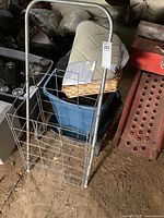 Vintage metal shopping cart leaning against a surface with beige bath mat and wicker tray around it.
