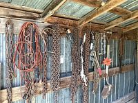 Wide view showing all chains, cables, a cable winch, tire chains, and shovel hanging on a wooden wall.