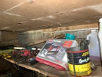 Wide shot of wooden shelf containing a boxed Coleman Powermate air nailer kit, cleaning brushes, scrapers and fluid bottles.
