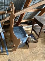 Photo showing wooden reindeer silhouette standing next to a plastic storage tote and cardboard box with Christmas decorations inside an attic space.