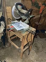 Full view of miter saw on wood stand with manual on table