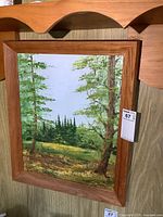 Full view of the signed oil painting in oak wood frame hanging on a wall.