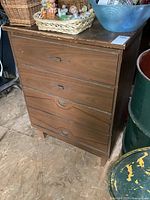 Front and side view of the vintage 4 drawer highboy dresser showing wood grain finish, metal handles, wear marks, and overall shape.