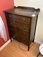 Front view of vintage solid wood high boy dresser, showing four drawers with round wooden knobs, minor surface wear on top.