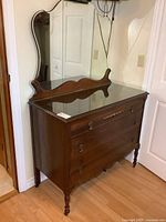 Front angle view of walnut dresser with mirror and glass topper showing drawer hardware and overall condition