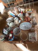 Wide view of table surface displaying many different household items including glass platters, dishes, baskets, and knick-knacks.