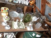 Wide view of assortment of glassware, porcelain dresser set, cookie jar and other kitchen items on wooden table