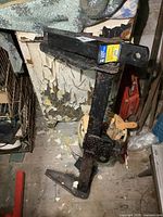 Photo of the black metal Hidden Hitch with surface rust, showing its vertical support and mounting base.