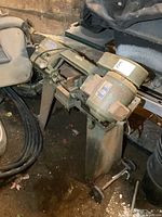 Full view of bandsaw mounted on pedestal stand with wheels, showing overall condition and location of motor