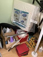 Photo showing white wedge-shaped cushion by Vita Care packed in plastic, various medical supplies in boxes including 3M barrier cream, blood pressure monitor, and other items stacked together.
