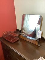 Mirror and wooden valet on a wooden dresser against a two-tone wall