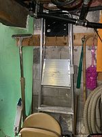 Front view of the aluminum painter's step ladder showing the platform step and black tool tray at the top, with surrounding items missing from ladder details.