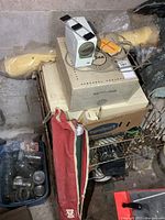 View of the items showing Kodak projector on original box, red carrying case for screen, white slide viewer, and other accessories.