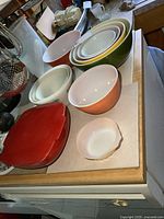 Multiple bowls and a red covered baking dish arranged on kitchen countertop
