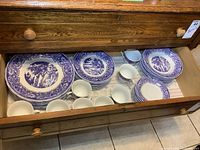 Wide view of open drawer showing 8 place settings of blue and white Royal Oak China including plates, cups, and saucers.