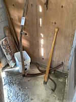 Full view of the three tools standing against a wooden wall showing wear and aged condition.