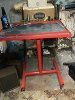 Front view of red mechanics work cart with screwdrivers on top in a workshop setting