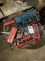 Overview of tray and cases containing various sized sockets and wrenches on a round metal surface