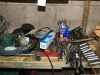 Photo showing a cluttered workbench with various hand tools including wrenches, ratchets, motors, and other tools packed together.