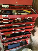 Red tool chest with multiple open drawers revealing sockets, wrenches and ratchets