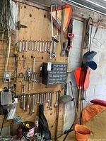 Image of a wall mounted organizer with multiple wrenches hung in size order along with hanging saws, signs, and a small compartment hardware organizer.