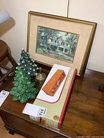 Overview photo showing two ceramic Christmas trees, framed print, brass bell, and boxed jewelry box on wooden surface.